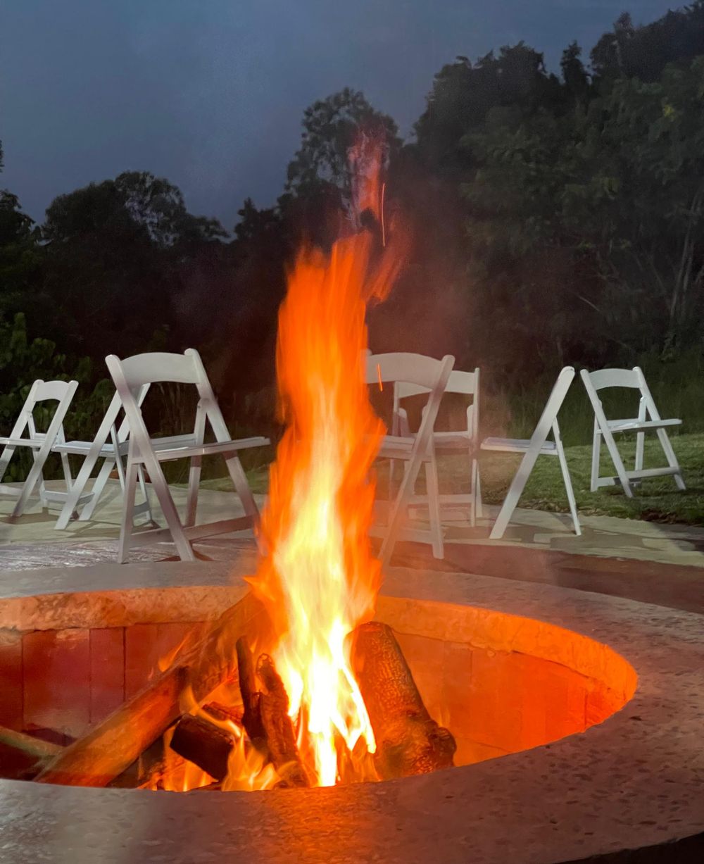An outdoor firepit with white event chairs at dusk at Maya Nature Resort.