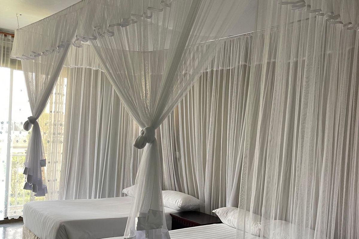 Twin canopy beds in a bright, sunlit room at Maya Nature Resort.