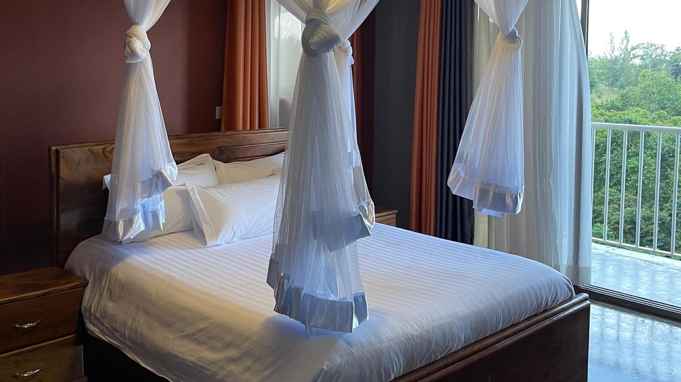 Room interior at Maya Nature Resort with a four-poster bed and valley-facing windows.